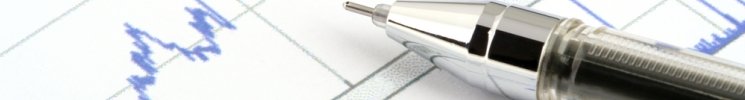 Image of a pen on top of papers with statistical reports containing a line graph.
